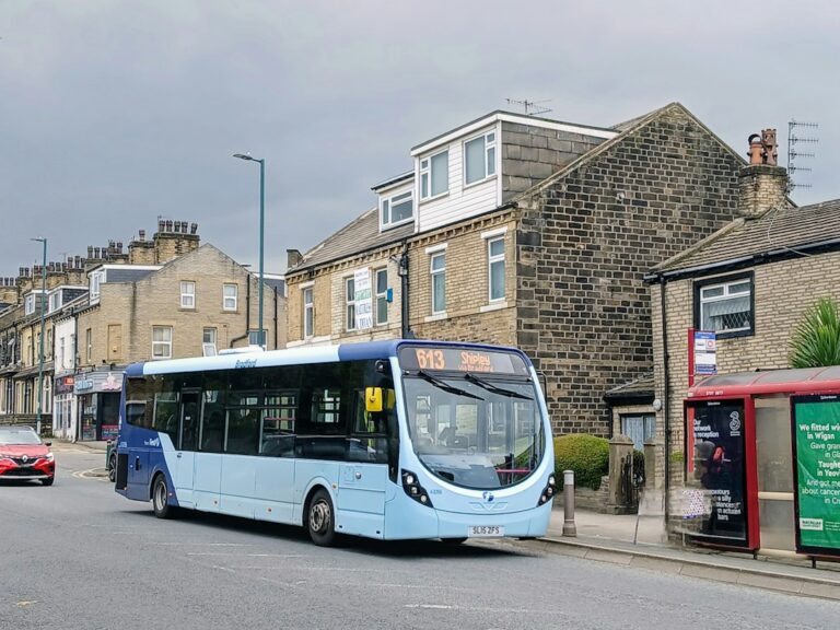 Local bus stopping at a bus stop in England with passengers boarding and getting off
