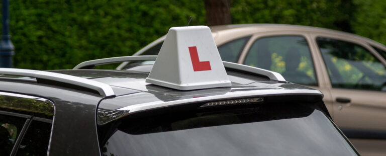 Learner driver car with a white roof sign displaying a red L
