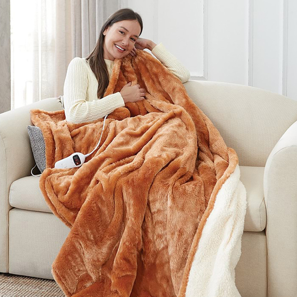 Electric reversible heated throw in warm brown fleece draped over a sofa